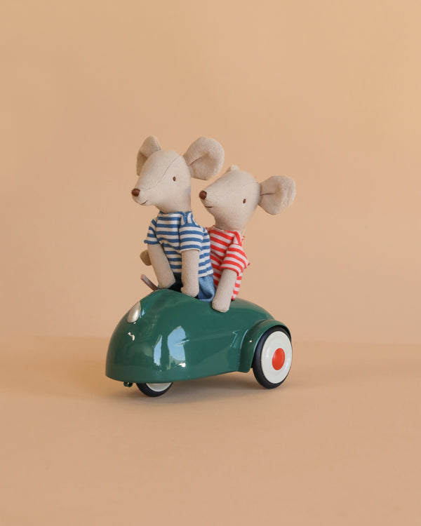 The Maileg Big Brother and Sister Adventure Set features two magnetic mice—one in a blue striped shirt, one in red—sitting together in a small green toy car against a plain beige background.
