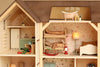 The Maileg Fully Furnished Farmhouse Set + Surprise Gift includes a wooden dollhouse complete with animal figurines, featuring a kitchen, a bedroom with bunk beds, a rocking horse, a lamp, and a bathroom with a clawfoot tub. Each room is adorned with floral wallpaper and petite furniture, enhanced by adorable Maileg Accessories and delightful Maileg Mouse Furniture.