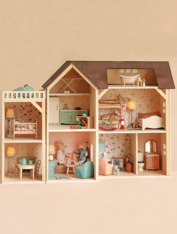 The Maileg Fully Furnished Farmhouse Set + Surprise Gift features a charming wooden farmhouse dollhouse with six beautifully decorated rooms—including a kitchen, living room, dining area, bathroom, and two bedrooms—each thoughtfully furnished with pastel-colored Dollhouse Accessories and delightful Maileg Mouse Furniture.