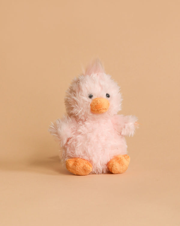 The Steiff Pipsy Pink Chick, a fluffy, light pink stuffed animal with an orange beak and feet, sits against a plain beige background.