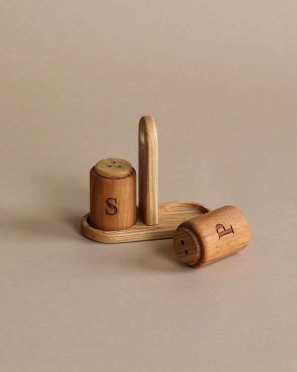 Pretend play wooden salt and pepper shakers with base. Beige background. 