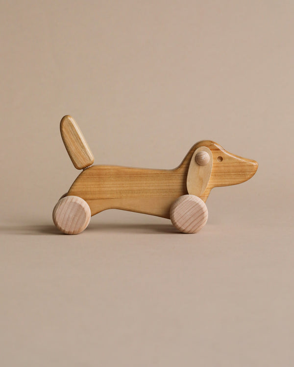 Natural color wooden dachshund dog push toy. 