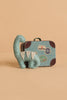 The Tiny Dinosaur Travel Set features a micro handmade felt dinosaur toy with white spikes, displayed in front of a blue and brown patterned Maileg suitcase on a beige background.