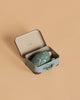 A Tiny Turtle Travel Set, featuring a small open suitcase with a handmade felt turtle inside, is displayed on a plain beige background.