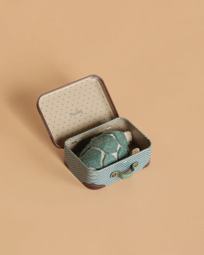 A Tiny Turtle Travel Set, featuring a small open suitcase with a handmade felt turtle inside, is displayed on a plain beige background.