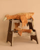 Two large Senger Naturwelt Cuddly Animal - Rust Geese are draped over a two-level wooden step stool against a beige background. The plush geese look soft and relaxed, with their heads and limbs hanging down.
