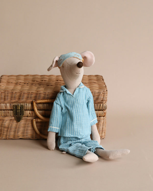 Maileg Maxi Mouse in Pyjamas, your perfect rest-time companion, is dressed in a blue striped pajama set with a matching nightcap. Seated against a wicker basket with a clasp, this charming stuffed toy stands out beautifully against the plain light beige background.