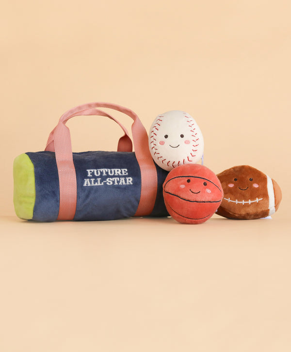 A Mon Ami Sports Play Bag labeled “Future All-Star,” featuring three smiling plush balls—a baseball, basketball, and football—crafted from soft polyester fibers, all displayed on a plain beige background. Spot clean to keep this adorable set looking its best.
