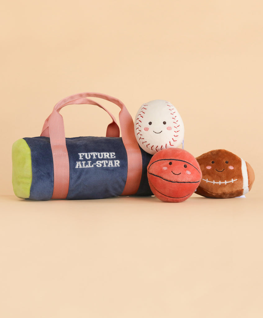 A Mon Ami Sports Play Bag labeled “Future All-Star,” featuring three smiling plush balls—a baseball, basketball, and football—crafted from soft polyester fibers, all displayed on a plain beige background. Spot clean to keep this adorable set looking its best.