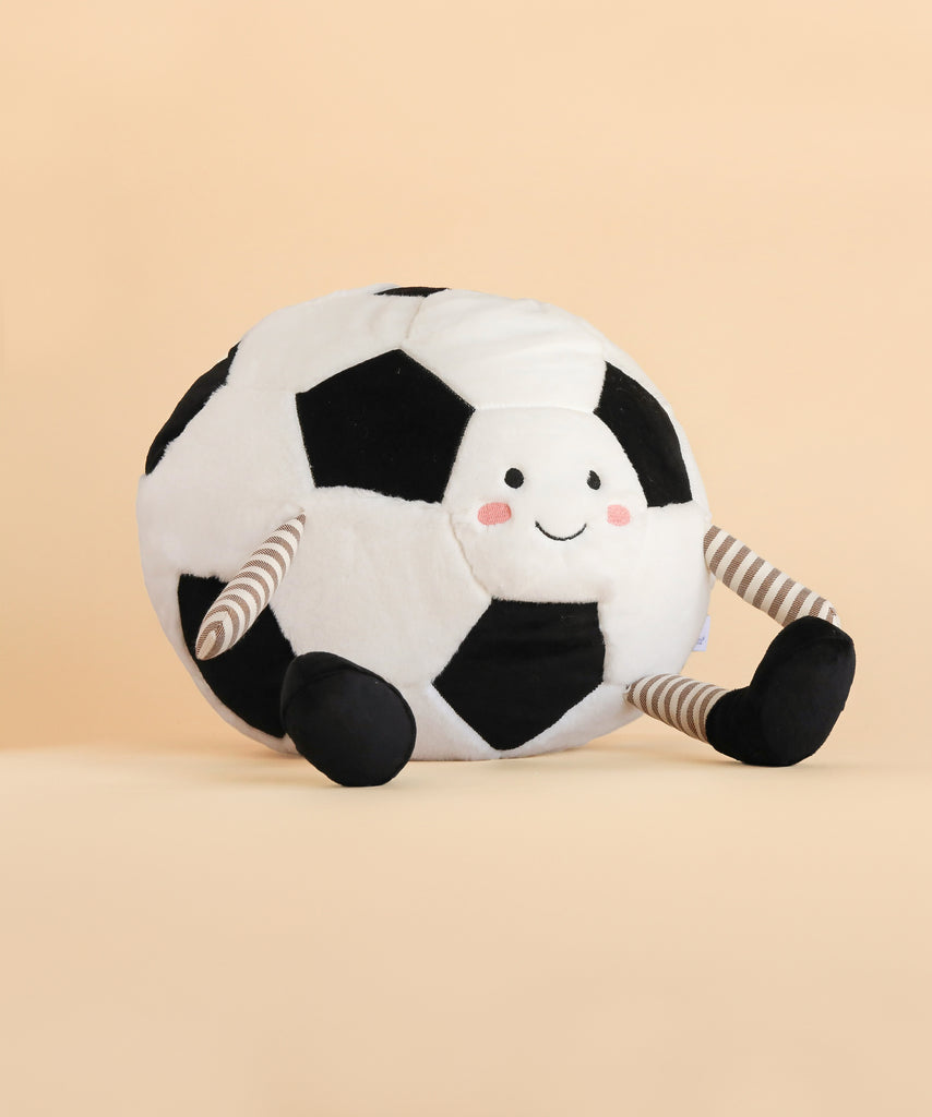 The Mon Ami - Sergio Soccer Ball - Large features a plush design with a smiling face, blushing cheeks, classic black and white patches, and striped legs with black feet. Sitting on a light beige background, it makes a perfect gift for soccer lovers.