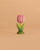 The Bumbu Handmade Wooden Flower Festive Tulip is a pink wooden tulip with green leaves on a green base—an eco-friendly piece perfect for Montessori toy collections, pictured against a plain beige background.