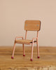 A charming wooden chair from the Maileg Family Celebration Set, featuring light pink metal legs with red tips, sits on a wooden surface against a beige background—perfect for enhancing your Maileg mouse collection or displaying delightful Maileg accessories.