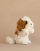 The Shih Tzu Dog Puppet is a fluffy, white and brown plush dog toy positioned on a plain beige background, facing to the right with its front paws raised as if begging or waving. Expertly crafted in the tradition of hand-sewn stuffed animals, this puppet captures charming details for a realistic plush animal look.