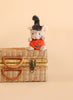 Bukowski - Mousy Pumpkin, a small Halloween stuffed animal mouse plush wearing a black witch hat and holding an orange pumpkin, sits atop a wicker basket with leather handles against a plain beige background.