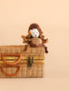 The Bukowski - Ziggy Spider plush toy, featuring a white face, sits atop a closed wicker picnic basket against a plain beige background, inviting imaginative play.