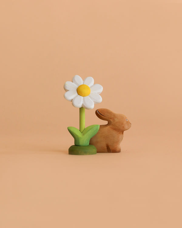 The Bumbu Handmade Wooden Spring Set features a bunny figurine and a white daisy with a yellow center and green stem, all displayed against a simple light peach background.