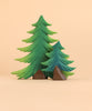 Two green handcrafted wooden fir trees of varying sizes from the Bumbu Handmade Wooden Fir Tree Set stand side by side, each resting on a small rock-shaped brown base, against a plain beige background. This charming set makes for delightful eco-friendly toys or decor.