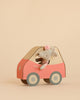 A Maileg Little Sister Driver Set, featuring a small mouse with a headband seated inside a pink and beige car, is displayed against a plain beige background.