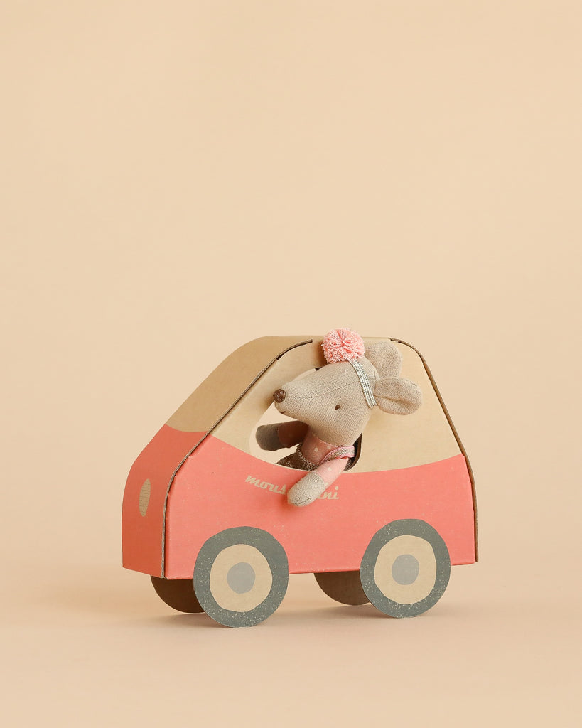 A Maileg Little Sister Driver Set, featuring a small mouse with a headband seated inside a pink and beige car, is displayed against a plain beige background.