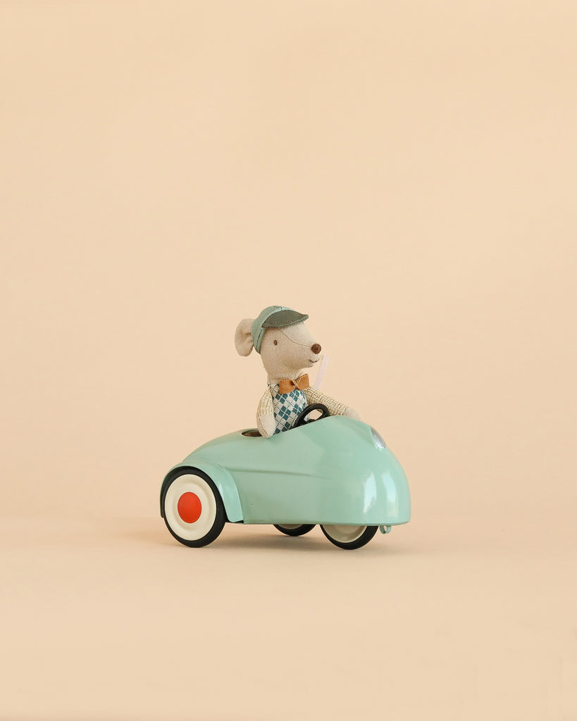 A Maileg Little Brother Driver Set features a small mouse wearing a blue cap and vest, sitting in a light blue toy car with white and orange wheels against a plain beige background.