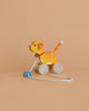 The Holztiger Pull-Along Cat is a wooden toy shaped like an orange tiger with yellow stripes, a pink nose, and a blue bone-shaped handle—an adorable toddler toy set against a plain beige background.