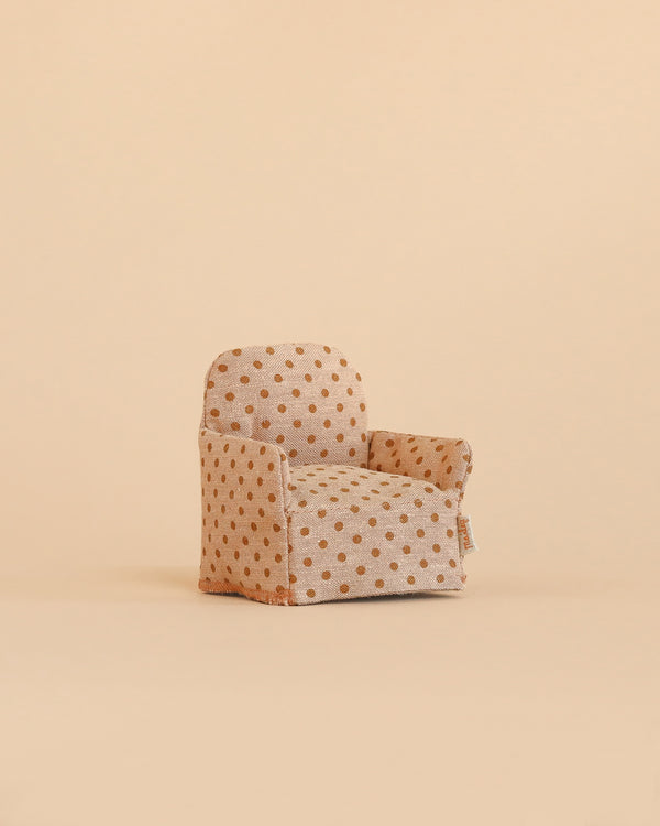 A small, beige Maileg Folding Chair for mice, decorated with brown polka dots, sits on a matching beige background—offering a minimalist and playful look that makes it perfect as a charming accessory for your dollhouse or as an adorable addition to your Maileg collection.