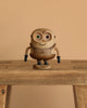 The Boyhood Minion Bob wooden figurine, featuring mismatched eyes and a "BOB" label on its base, stands on a wooden table with a plain beige background.