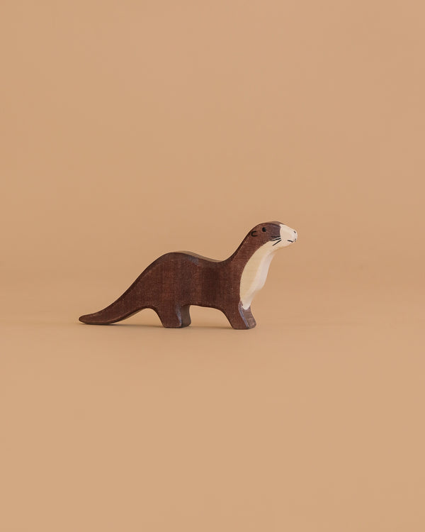 The Holztiger Sea Otter is a small, handcrafted wooden figurine with brown and cream coloring, standing on a light brown background—a charming toy made in Europe.