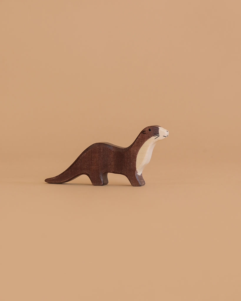 The Holztiger Sea Otter is a small, handcrafted wooden figurine with brown and cream coloring, standing on a light brown background—a charming toy made in Europe.