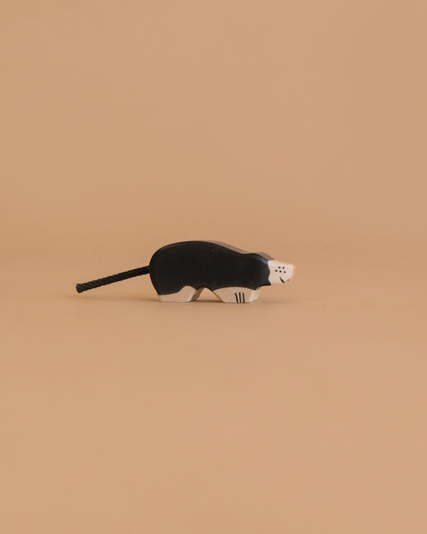 The Holztiger Mole, a handcrafted wooden figurine with black and white details, highlights the charm of HOLZTIGER European toys, shown against a plain beige background.