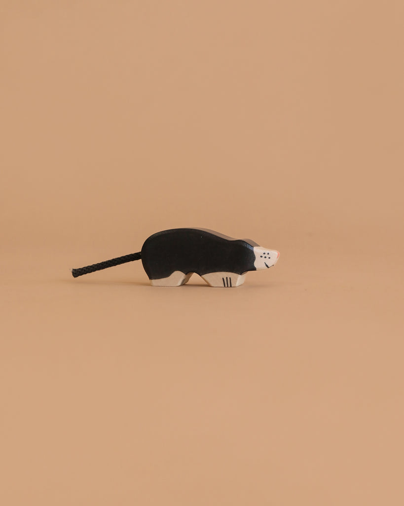 The Holztiger Mole, a handcrafted wooden figurine with black and white details, highlights the charm of HOLZTIGER European toys, shown against a plain beige background.