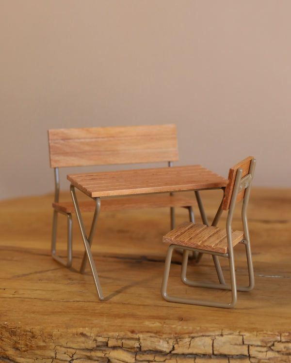 The Maileg Garden Table & Chair Set - Mouse Size features a miniature setup with a wooden table and two chairs with metal legs, perfect as a cozy garden set or tiny classroom for a mouse family.