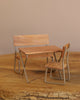 A small wooden table with two matching chairs, all with metal legs, sits on a wood surface next to the Maileg Woodland Picnic Set, against a plain beige background.