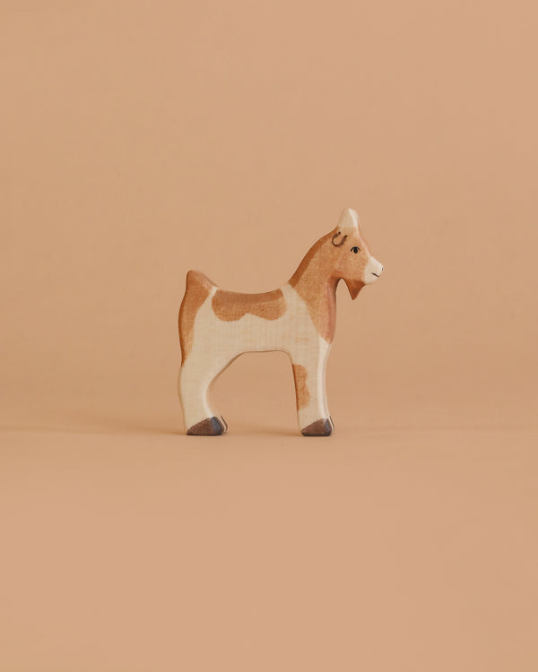 The Holztiger Goat is a small, handcrafted wooden toy with brown and white markings, a simple hand-painted design, and a friendly expression—just like classic HOLZTIGER figures made in Europe.