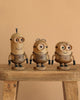 The Boyhood Minion Bob wooden figurine stands on a bench against a beige background, featuring a unique hairstyle, charming expression, and holding a tiny stuffed teddy bear.