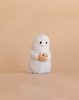 The Cuddle + Kind Baby Ghost with Pumpkin is a small, fluffy white plush shaped like a baby ghost holding a tiny knitted orange pumpkin, shown against a plain light beige background.