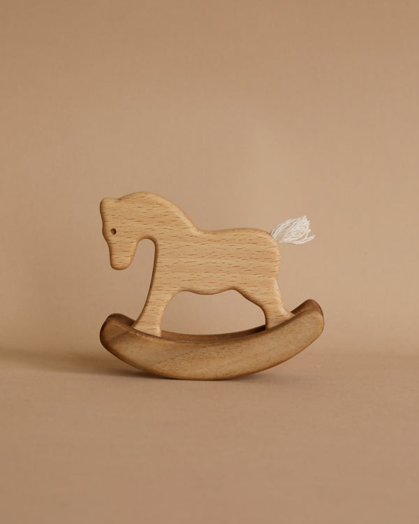Small Handmade Wooden Rocking Horse for children placed against a beige background. The horse is in a rocker style with a small white tail, showcasing a simple and minimalist design.