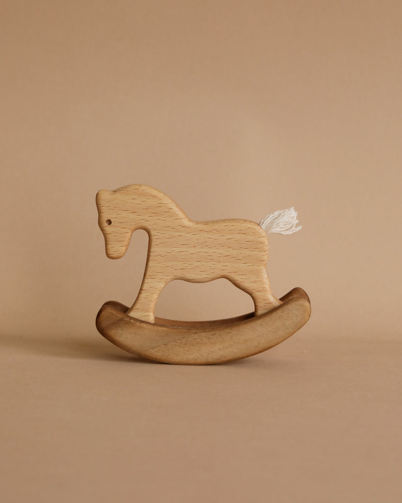 Small Handmade Wooden Rocking Horse for children placed against a beige background. The horse is in a rocker style with a small white tail, showcasing a simple and minimalist design.