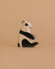 The Holztiger Panda Bear, Sitting is a handcrafted wooden figurine with a minimalist design, painted in black and white. It sits on a beige surface against a matching background, showcasing the charm of European-made wood toys.