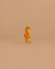 The Holztiger Seahorse is a small, yellow-orange wooden toy with red markings, standing upright on a light beige background—a charming handcrafted figure made in Europe.