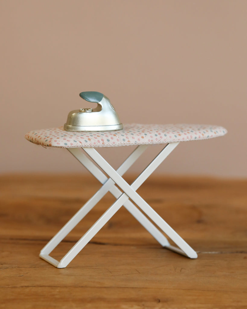 The Maileg Laundry Room Set features a small toy ironing board with a matching toy iron, both displayed on a wooden surface—ideal for imaginative Maileg ironing play sessions.