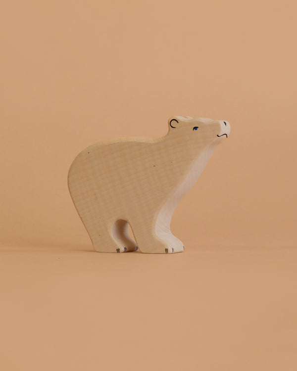 The Holztiger Polar Bear, a light-colored wooden figurine handcrafted in Europe, stands on a beige surface with a matching background.