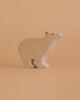 The Holztiger Polar Bear, a light-colored wooden figurine handcrafted in Europe, stands on a beige surface with a matching background.