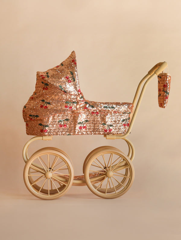 Konges Sloejd Mini Doll Pram - Sparkly Cherry Sequin with a sequined carriage featuring a cherry pattern, set on a beige frame with four large wheels.