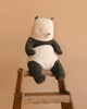 The Maileg Panda Stuffed Animal, Large, with black and white cotton fur, sits atop a wooden ladder against a plain beige background.