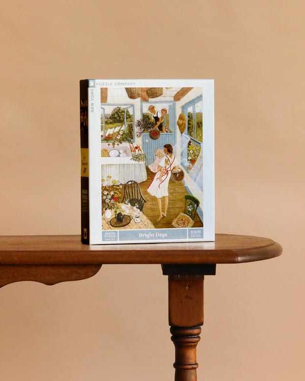 A Bright Days - 1000 Piece Jigsaw Puzzle box featuring a woman in a vibrant, cozy room stands upright on a wooden table with a plain beige background.