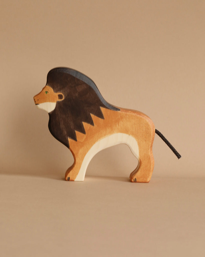 Part of the Holztiger Handmade Wooden Safari Animals Set, this wooden lion toy stands proudly with a dark brown mane, light brown body, white underside, and black tail on a neutral beige surface.