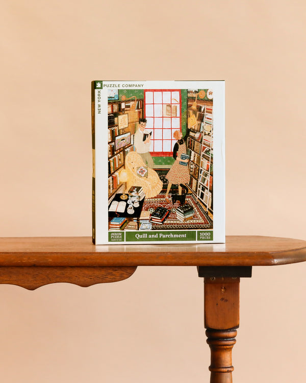 Quill and Parchment - 1000 Piece Jigsaw Puzzle rests on a wooden table, showing an illustrated scene of two people in a cozy bookstore filled with bookshelves and a large window.