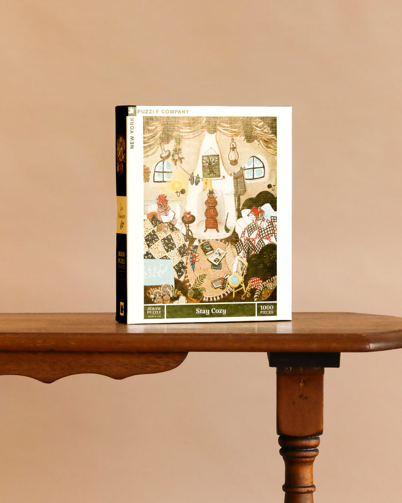 Stay Cozy - 1000 Piece Jigsaw Puzzle features animals in a festive room with books, warm lighting, and a window—set on a wooden table, it’s the perfect holiday gift.