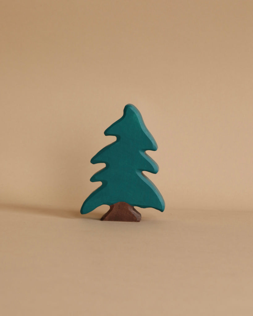 A simple wooden tree figurine with a brown base and dark green foliage stands against a plain beige background. The Holztiger Conifer Tree, part of the handcrafted wood toys collection by HOLZTIGER figures, has a stylized, minimalist design with smooth curves and simplistic features. Made in Europe.